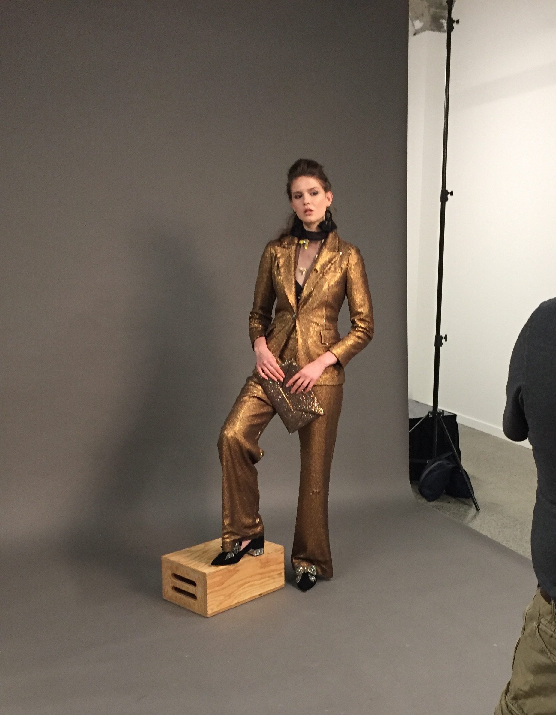 A model in gold suit posing during a photo shoot.