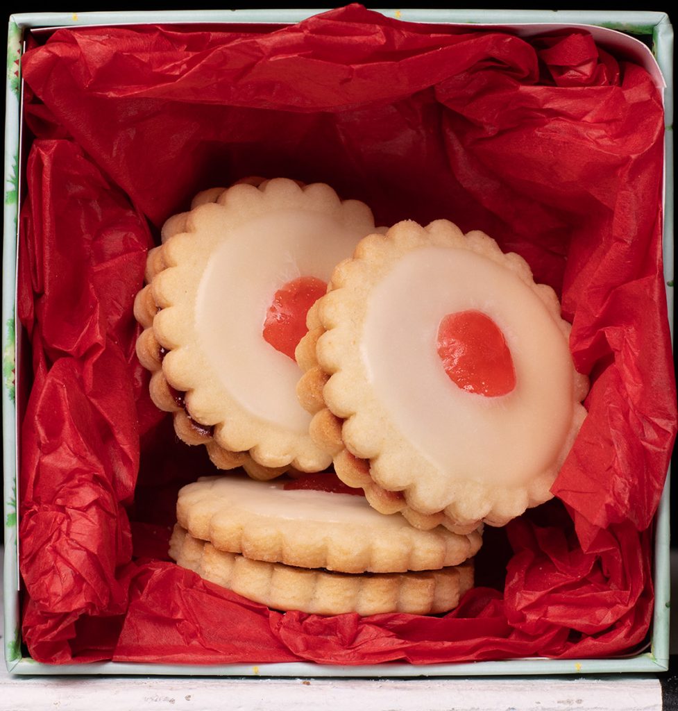 Empire cookies in a box with red tissue paper