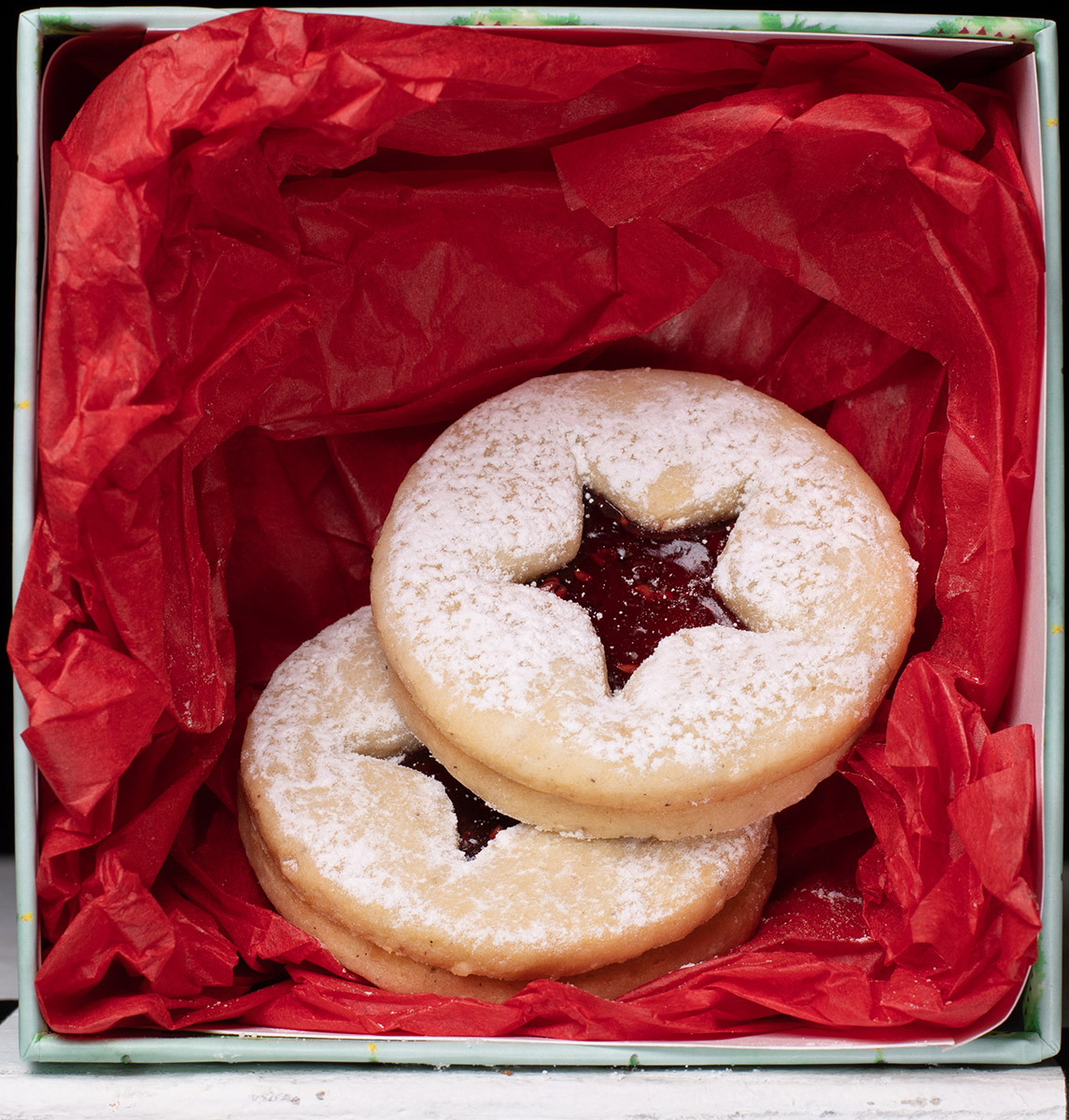 Linzer cookies in a box with red tissue paper