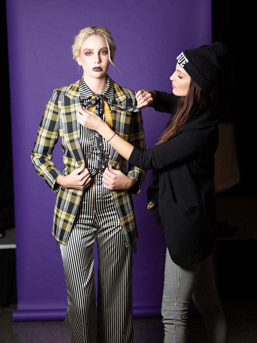 A wardrobe stylist adjusting the top on a female fashion model