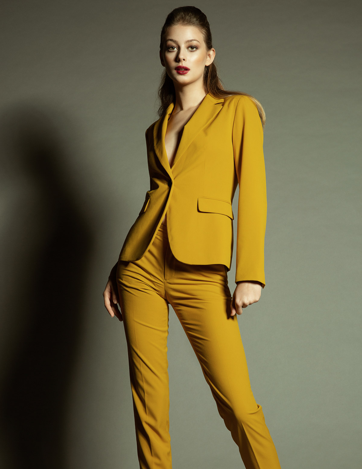 A fashion model posing in an all mustard coloured suit