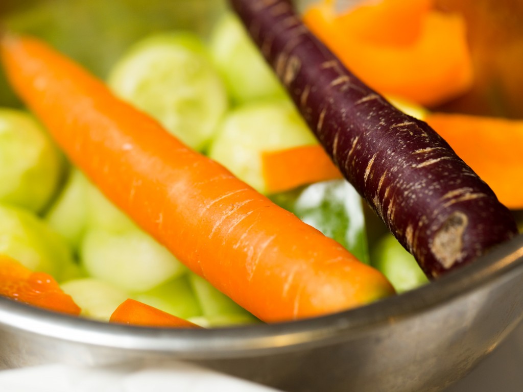 A bowl of vegetables featuring orange and purple carrots