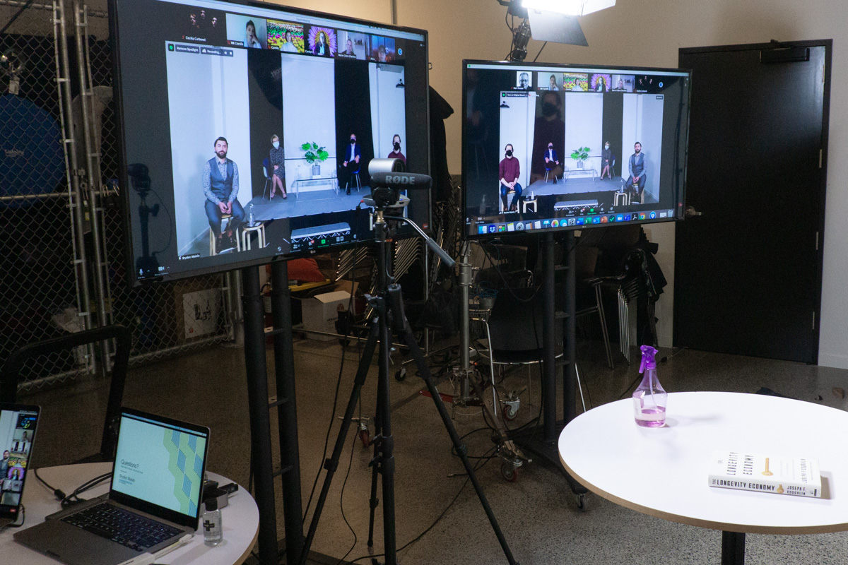 Photo of two TV screens showing the webinar in progress with several people on screen